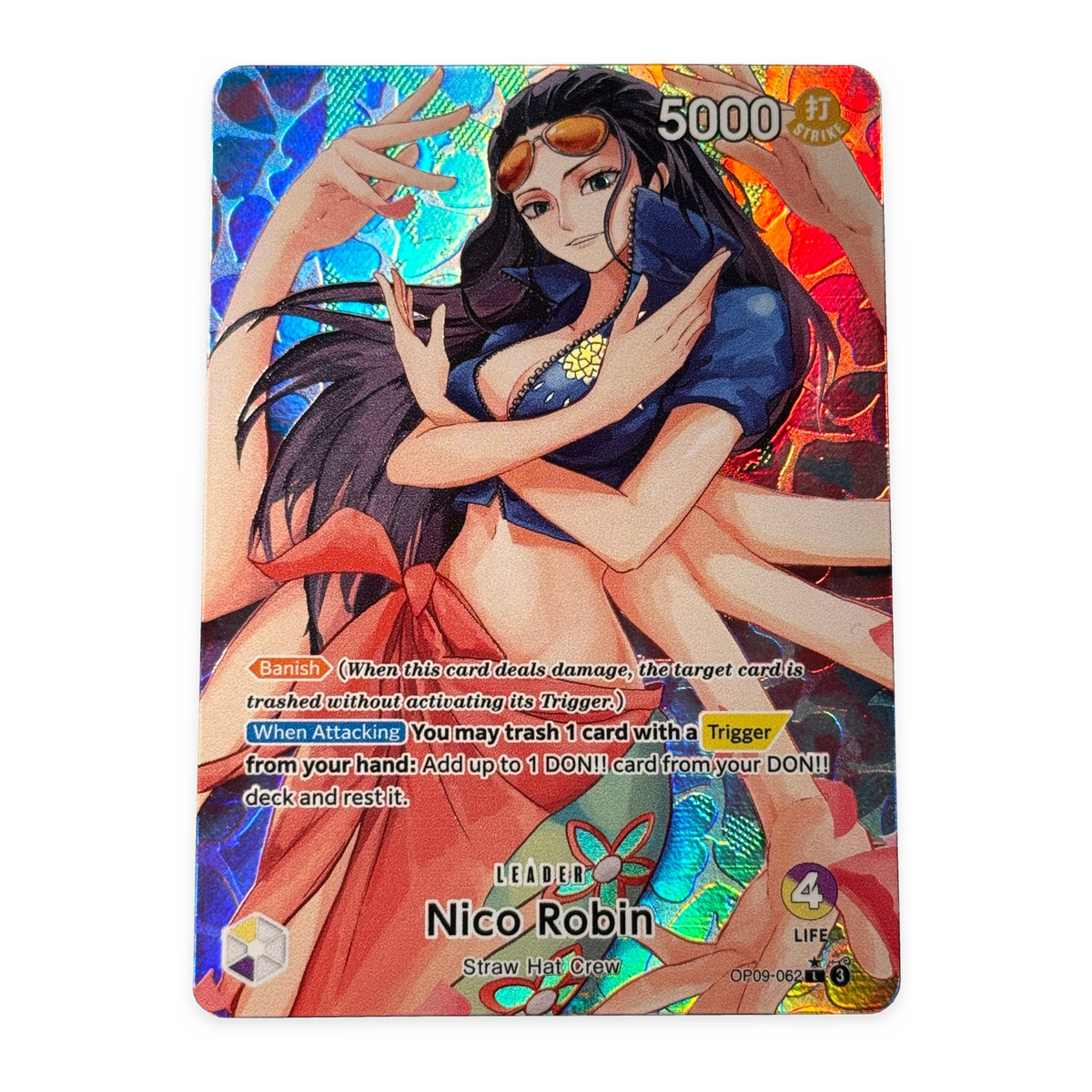 A holographic trading card featuring an anime-style female character with long black hair, a blue top, and a red skirt. The card includes game text, a 5000 power indicator, and the name Nico Robin at the bottom.
